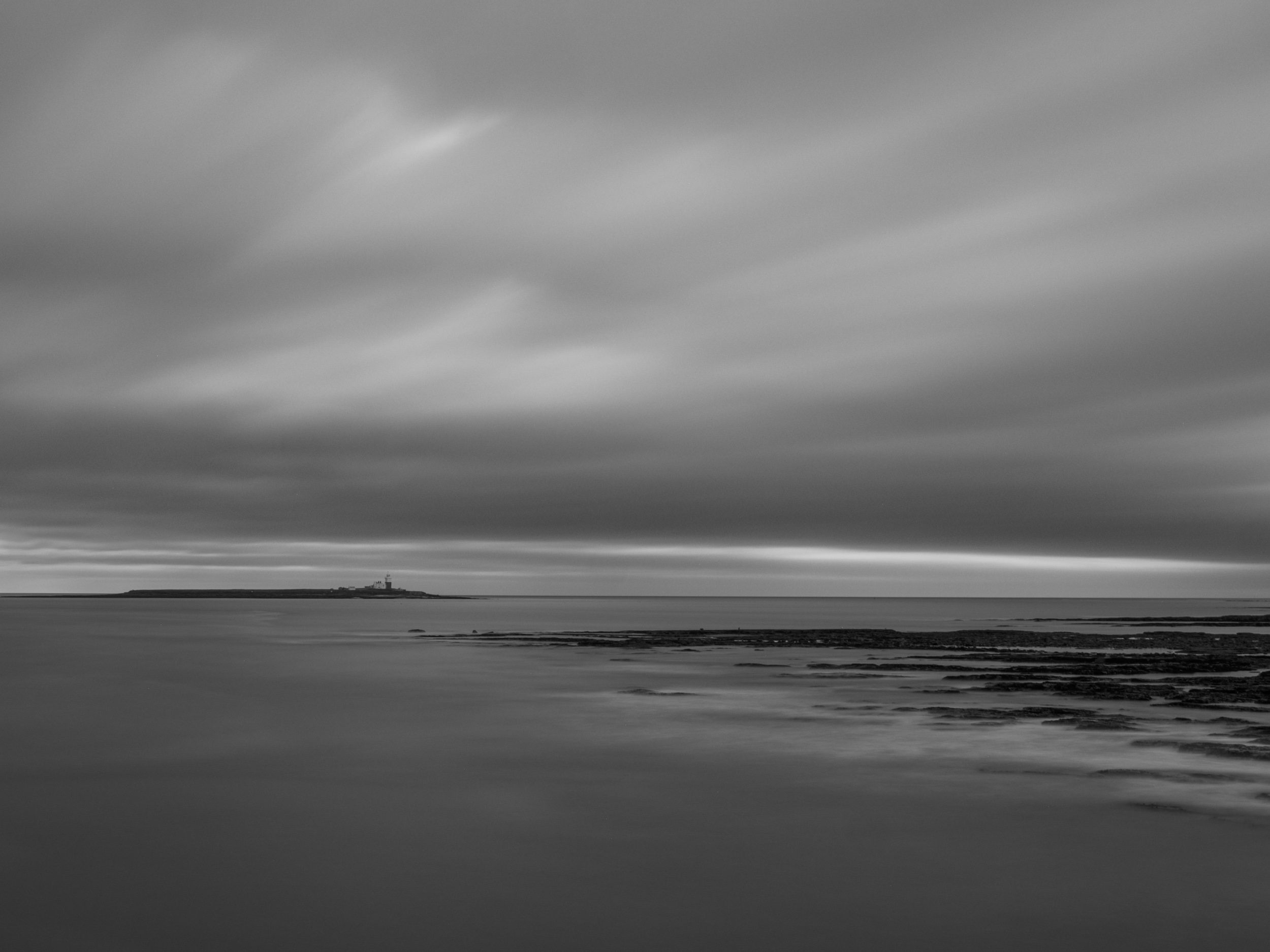 Long exposure black and white image looking to sea with Coquet Island on the horizon.